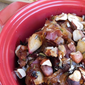 Un brie fondant garni de pommes, de bacon et de noisettes dans un caquelon. 