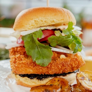 Un burger végétariens de portobello dans une assiette avec des pommes de terre rôties.