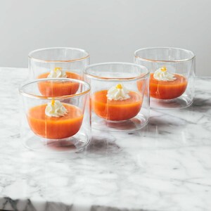 Des petits verres contenants des cappuccino de carottes garnis de crème fouettée à l’orange.