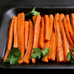 Plusieurs carottes en bâtonnets dans une assiette.
