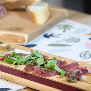 Des tranches fines de viandes sur une planche de bois.