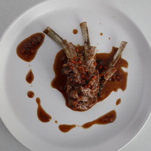 Un carré d'agneau dans une assiette avec une sauce au porto.