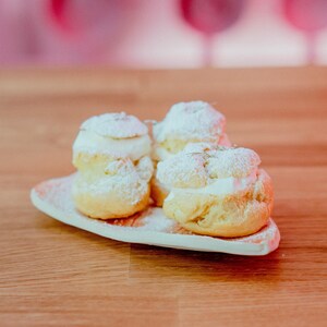 Quatre choux farcis de crème fouettée dans une assiette.