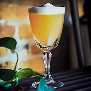 Un cocktail jaune dans un verre avec de la mousse.