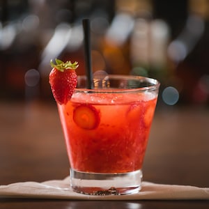 Un cocktail rouge décoré d'une fraise.
