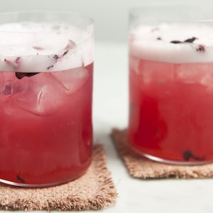 Deux verres de cocktail La Rosée servies sur des sous-verre en jute.