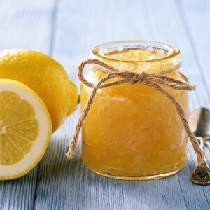 Un pot de marmelade aux côtés d'une citron entier et d'un demi-citron.