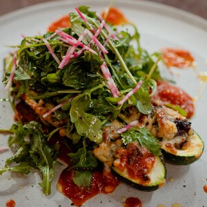 Deux courgettes farcies avec une salade verte par-dessus.