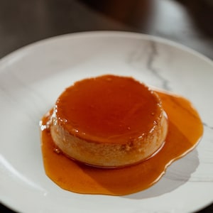 Une crème caramel dans une assiette blanche.