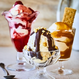 Il est possible de voir trois coupes de crème glacée, toutes avec un coulis et une garniture différente. 