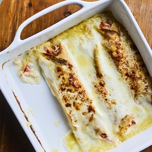 La recette de crêpes au crabe dans un plat blanc carré avec un morceau dans une assiette juste à côté. 