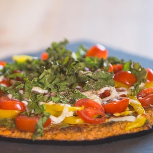 Une pizza garnie de légumes et des fines herbes.