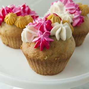 Trois cupcakes à la vanille avec du glaçage, servis sur un piédestal à gâteau.