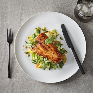 Un filet de truite déposé sur une salade dans une assiette.
