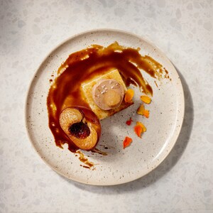 Du foie gras, une pêche poêlée, un coulis de sauce dans une assiette. 