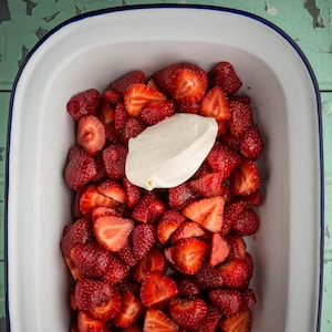 Un plat de service avec des fraises coupées en morceaux et de la crème glacée.