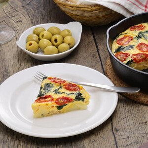 Un poêlon en fonte contenant la frittata ainsi qu'un morceau de frittata dans une assiette.