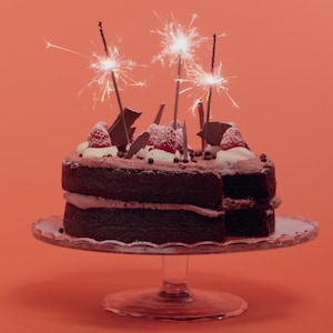 Un gâteau au chocolat garni de crème fouettée, de framboises et de copeaux de chocolat.