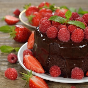 Un gâteau mi-cuit au chocolat nappé d'un crémage au chocolat coulant et décoré de framboises et fraises fraîches.