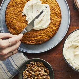 Une main est en train de glacer un gâteau avec le glaçage au fromage à la crème.