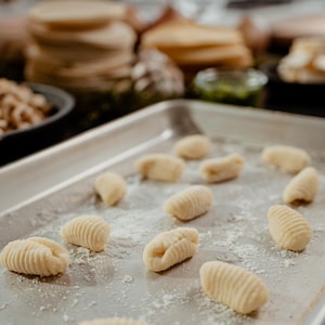 Plusieurs gnocchis sur une plaque avec de la farine.