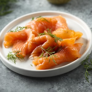 Du saumon gravlax dans une assiette blanche avec de l'aneth.