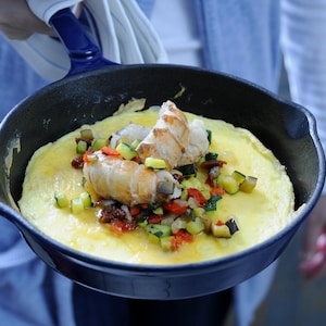 Une poêle en fonte avec une omelette aux langoustines et ratatouille.