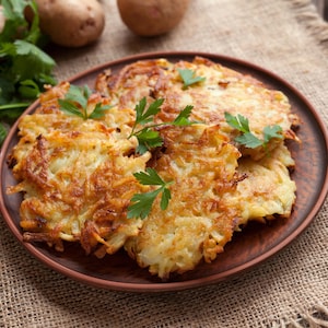 Quelques latkes dans une assiette avec quelques feuilles de persil.