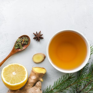 Un bol rempli de thé avec du citron, du gingembre et des épices sur la table.
