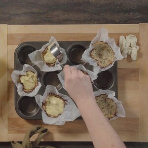 Une personne verse de la préparation dans un moule à muffins. 