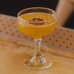 Un verre rempli d'un mocktail orangé avec une rondelle de citron déshydratée.