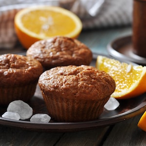 Des muffins à l'orange et aux dattes ainsi que des quartiers d'orange dans une assiette.