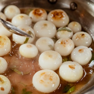 Des oignons cipollinis en train de cuire dans une poêle.