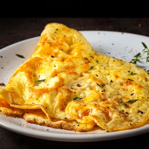 Une omelette au fromage dans une assiette, garnie de fines herbes.