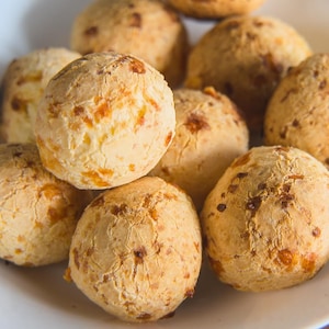 Des petits pains en forme de boules, grillés, dans une assiette creuse.