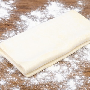 Un pâton de pâte feuilletée inversée sur un comptoir en bois.