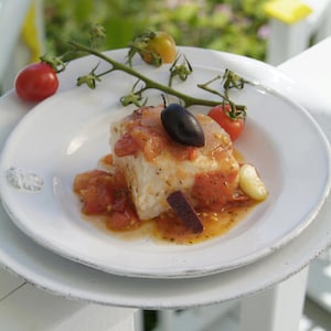 Un pavé de bonite à dos rayé avec une sauce tomatée et une olive noire sur le dessus.