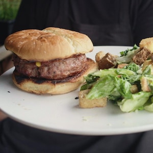 Un burger et une salade César présentés sur une assiette.