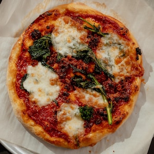 Une pizza à la tomate, au rapini et au tempeh sortant du four.