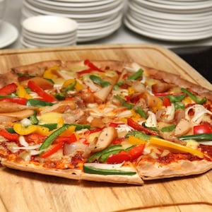 Une pizza au poulet sur une planche à découper.