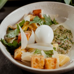 Des croûtons, un œuf dur et des légumes dans un bol avec une sauce ravigote.