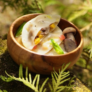 Ravioles farcis de champignons et de morceaux de courge musquée dans un petit bol en bois.