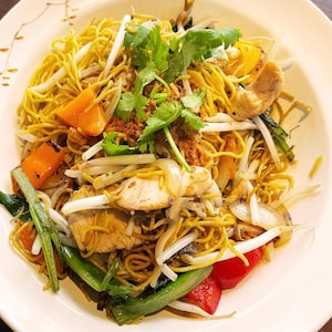 Un plat de nouilles sautées au poulet et aux légumes.