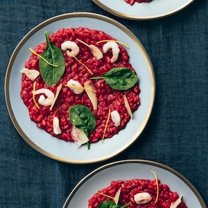 Des assiettes de risotto sanguin avec des crevettes et des épinards.
