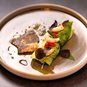 Un rouleau de laitue garni de crevettes et de feuilles de mélisse, nappé d'une vinaigrette légère, dans une assiette.