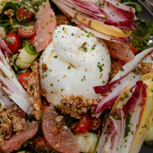 Une salade avec une burrata au centre.
