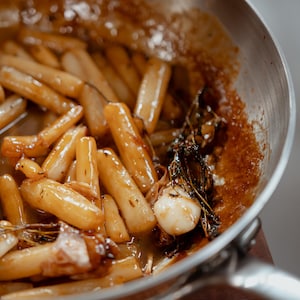 Une poêle remplie de salsifis à la demi-glace de veau.