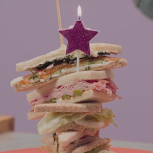 Une pile de sandwichs sans croûte: un au saumon fûmé, un au jambon et aux cornichons, ainsi qu'un aux oeufs et au wasabi.