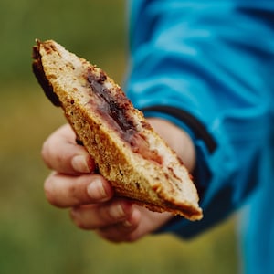 Il est possible de voir la main de Geneviève tenir un morceau de sandwich grillé. 