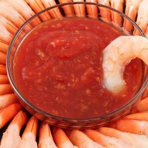 Un plat de sauce cocktail au centre d'une couronne de crevettes.
